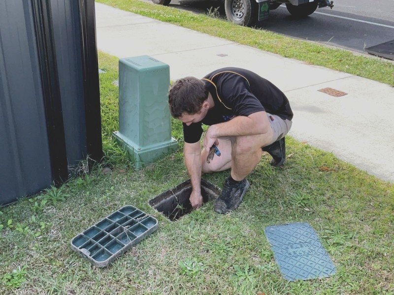 Genies plumber lifting a drain grate to check a blockage